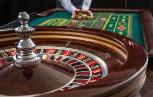 Ruleta y montones de fichas de juego en una mesa verde de casino. Hombre mano sobre fichas de casino - apuesta.